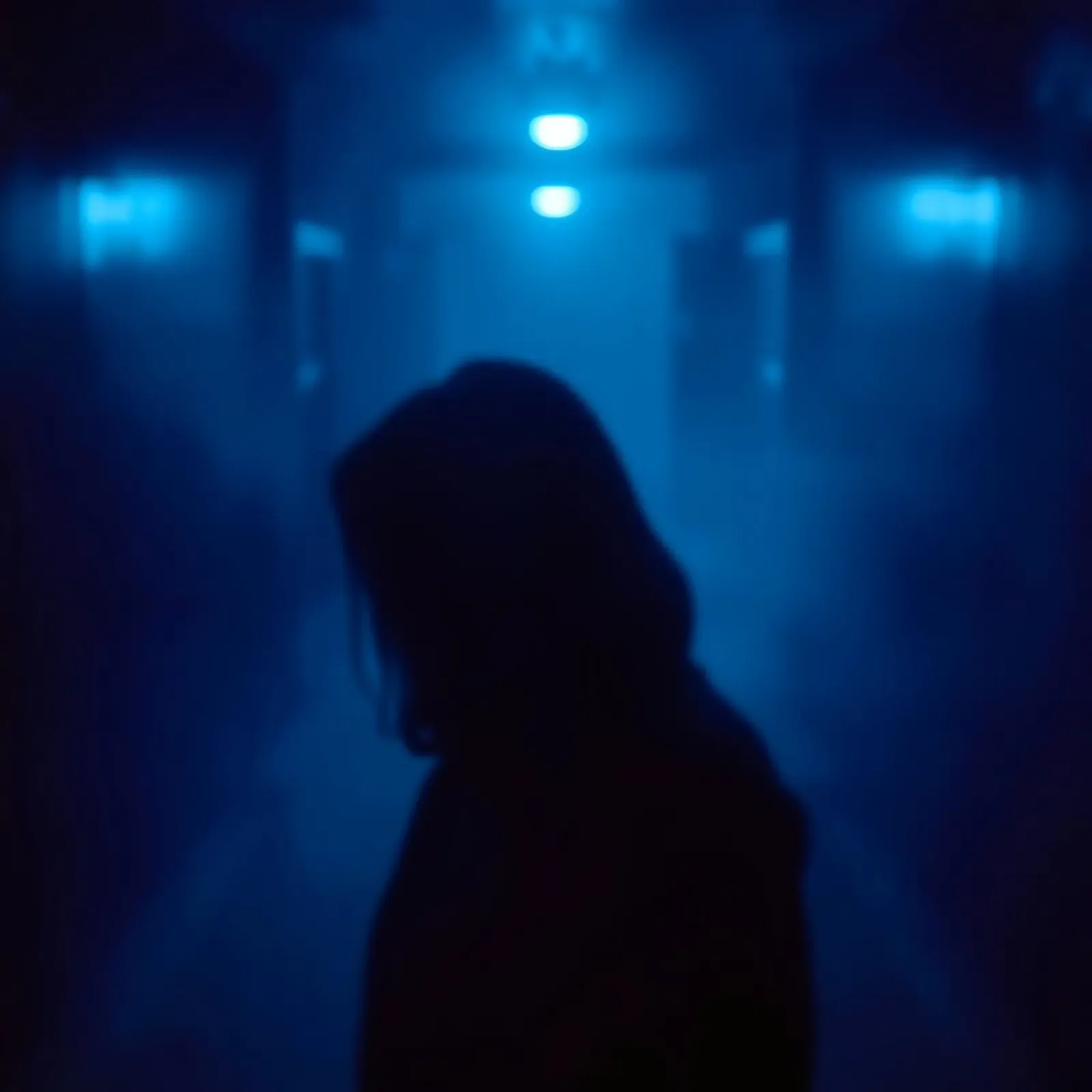 Donna in un corridoio poco illuminato con luci blu e nebbia pellicola backlit da DesignDoodle
