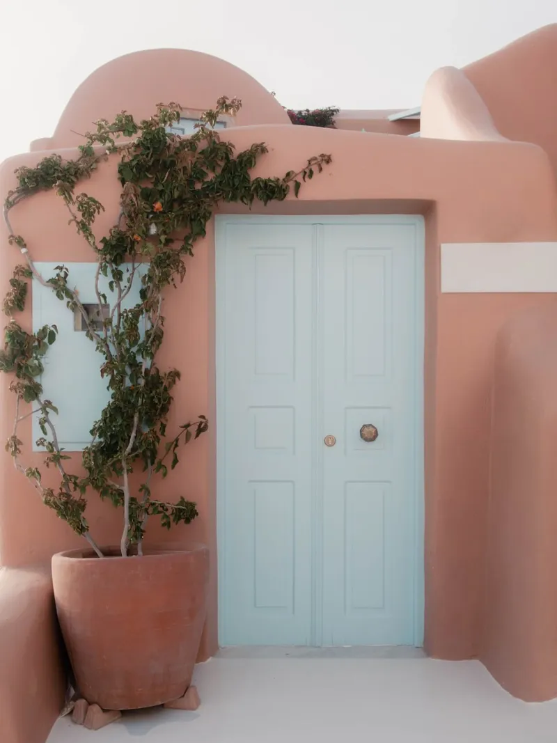 Edificio in terracotta con porta blu - Santorini, Grecia pellicola backlit da Kimberley Jekel Photography