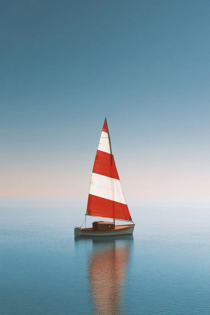 Rotes und weißes Segelboot auf ruhiger See Leinwand von Indigo Tides Art