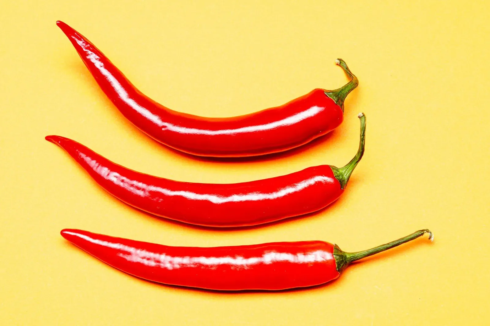 Piment rouge sur surface jaune hahnemühle de Bilderwelt - Kunst für die Wand