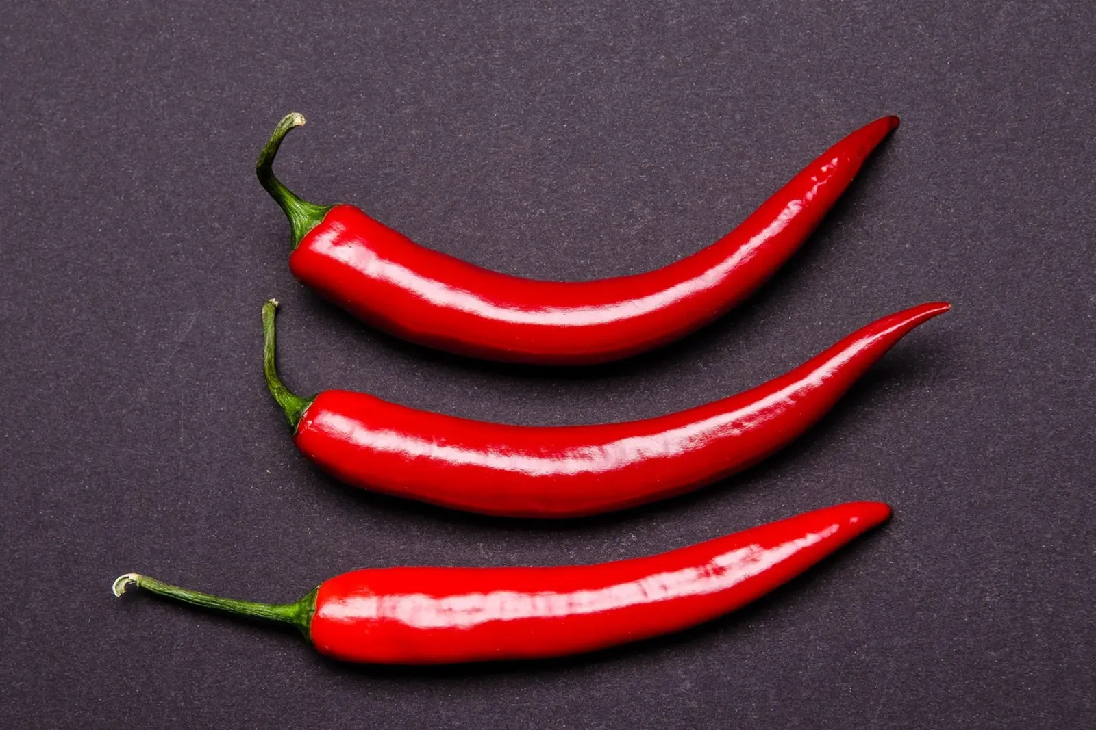 Three chilli peppers on a black background hahnemühle by Bilderwelt - Kunst für die Wand