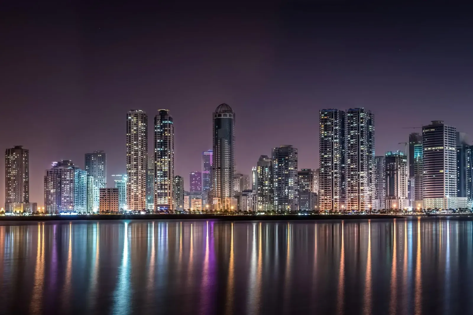 Luci della città sull'acqua, Sharjah, Emirati Arabi Uniti poster con telaio in legno da Wanderlust Vibes