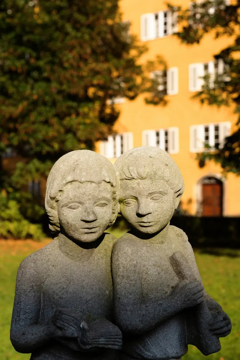 Due statue di bambini nel Borstei di Monaco di Baviera pellicola backlit da Borstei München