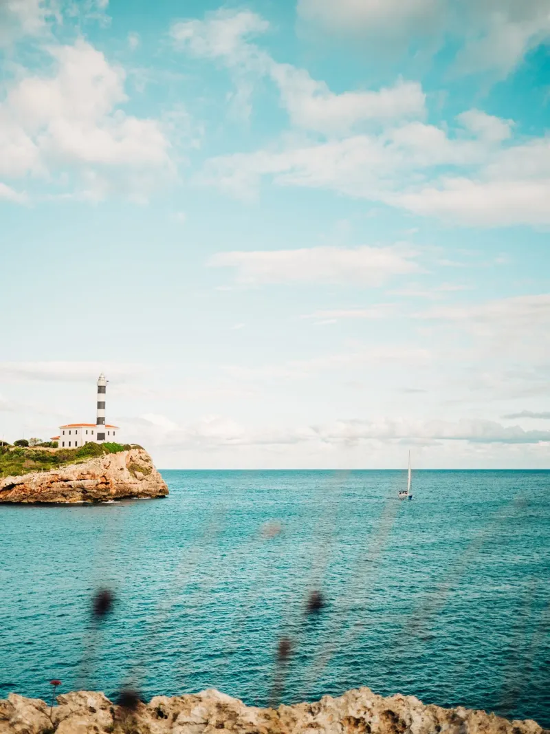 Lighthouse by the sea off Mallorca with sailing boat canvas by Bold and Retro